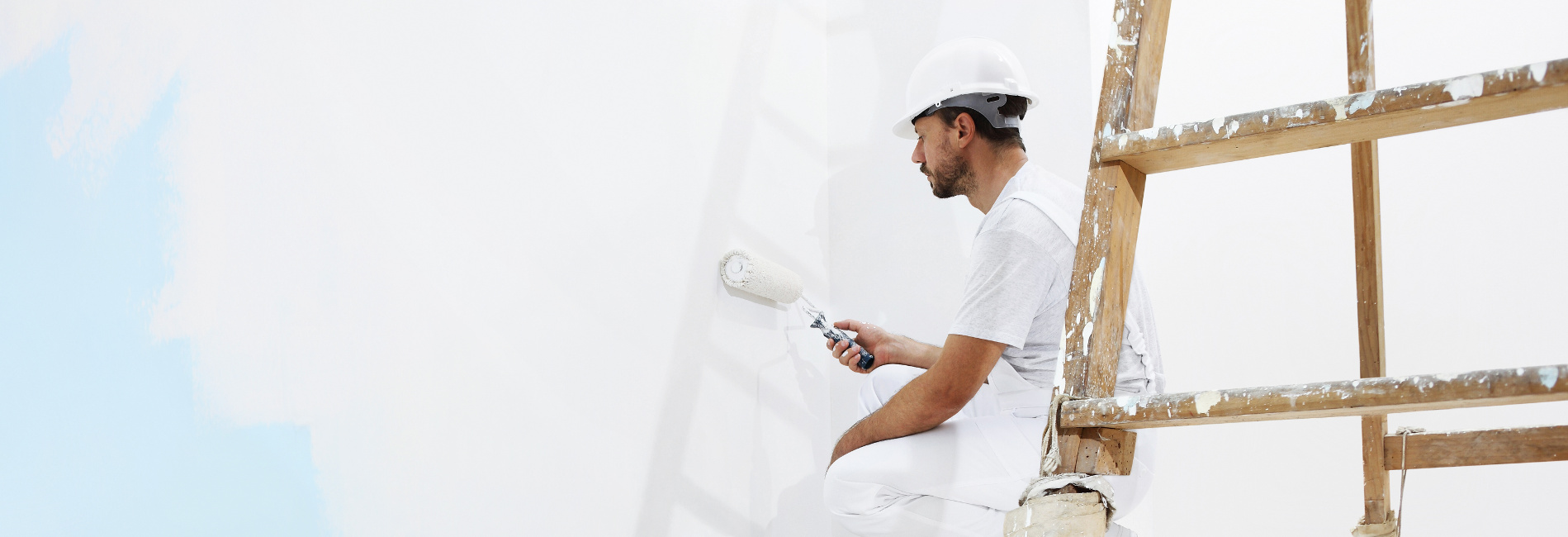 Maler streicht eine weiße Wand